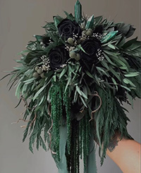 bouquet with black roses surrounded in green flowers, branches and leaves draped with crystals embedded